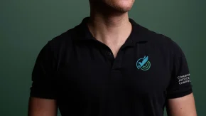 a man wearing a black cjc polo with a logo on the chest and sleeve